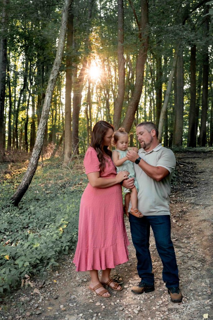 Family Snuggles close during a golden hour family photo session in the woods of Akron, Ohio with photographer Brittney Emerson behind the camera