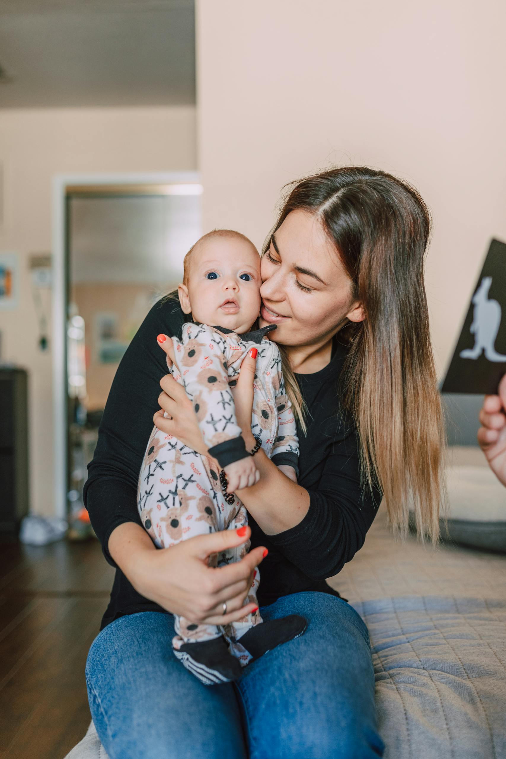 A loving mother holds her newborn baby indoors, capturing the essence of warmth and family bonding.